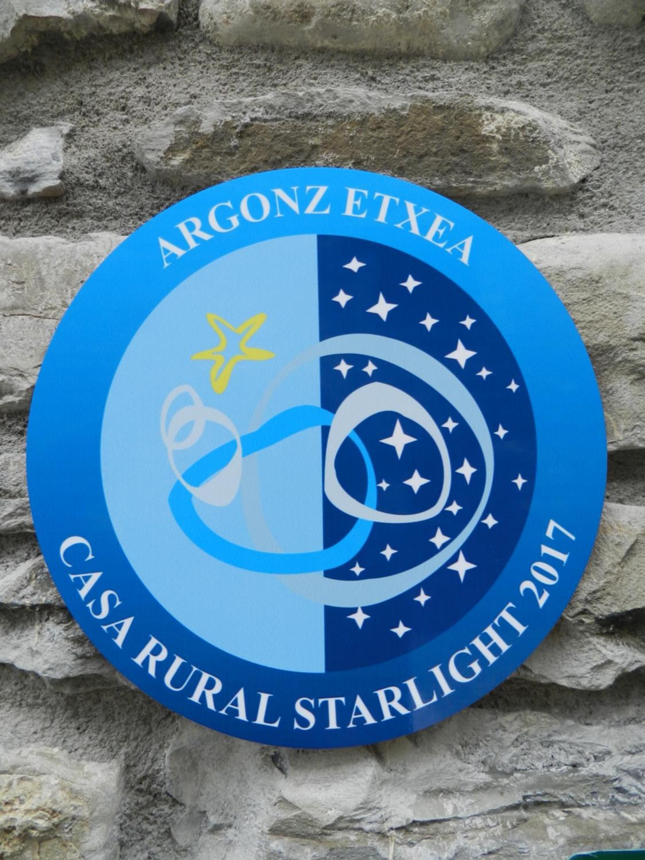 A circular sign with the text 'ARGONZ ETXEA CASA RURAL STARLIGHT 2017' and a graphic of a star and a crescent moon.