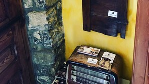 A narrow stone-walled corridor with a wooden door and a small table with magazines. - Casa Rural Argonz Etxea (Urzainqui)
