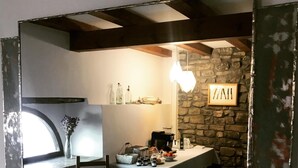 A dining area with a stone wall, a table set with various items, and a window with a view. - Casa Rural Argonz Etxea (Urzainqui)