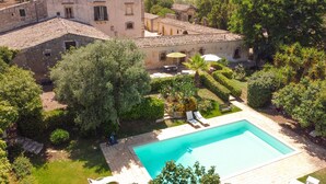 Un patio con piscina, rodeado de abundante vegetación y edificios históricos.