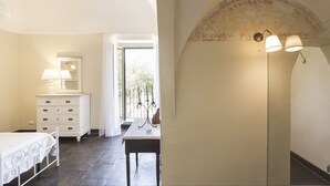 Un dormitorio con cama, cómoda, mesa y lámpara.