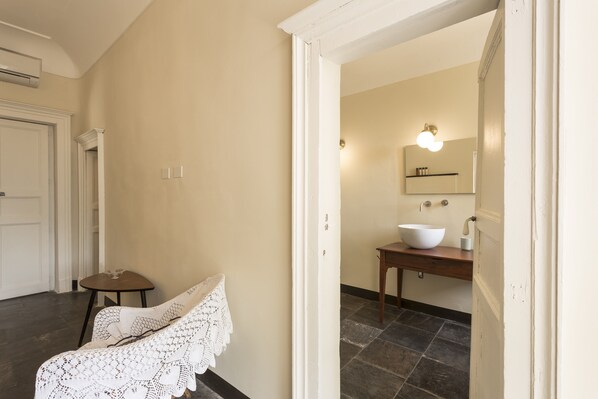 A hallway with a white door, a small table with a glass, and a white crocheted chair.