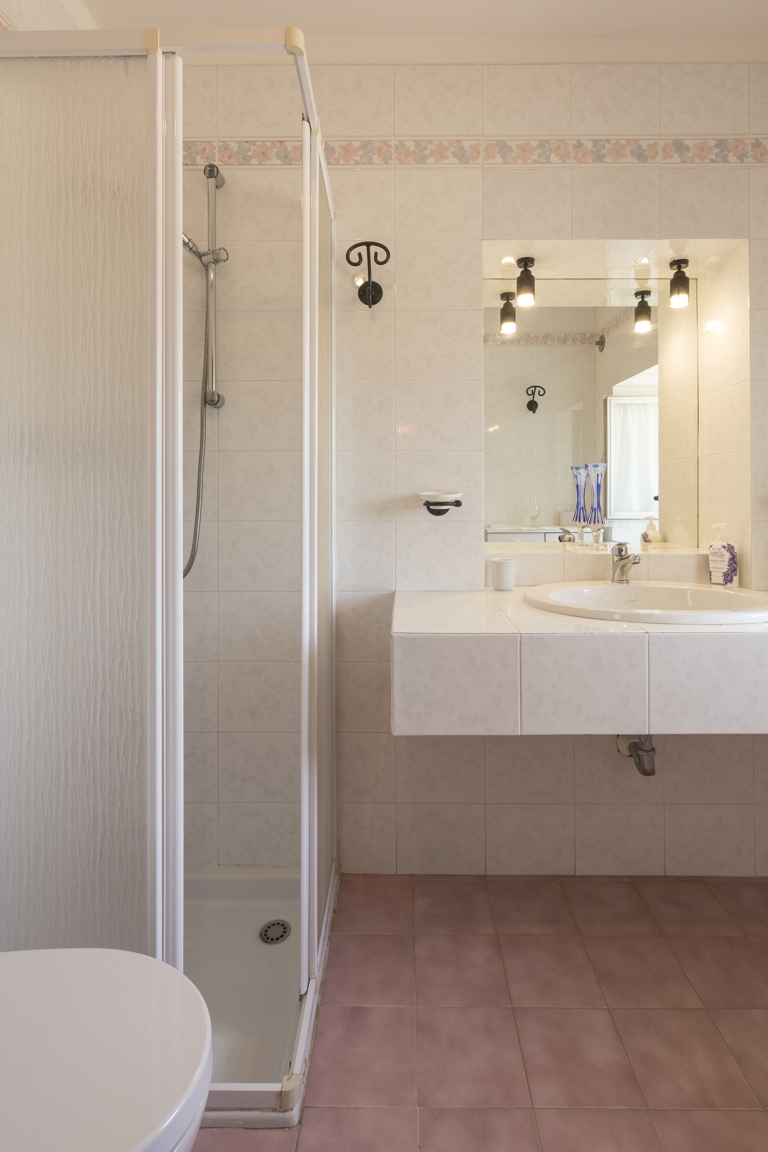A bathroom with a glass-enclosed shower, a sink with a mirror, and a toilet.