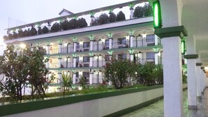 A multi-story hotel with balconies, a covered walkway, and a landscaped area with plants. - Hotel Marques De Cima (Nogales)