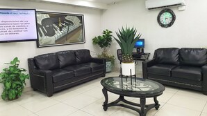 A modern waiting area with two black leather sofas, a glass coffee table, and a large framed artwork on the wall. - Hotel Marques De Cima (Nogales)