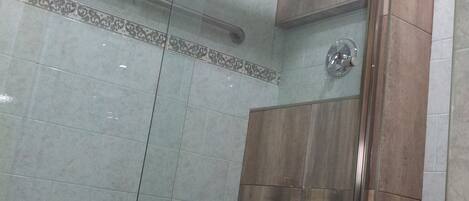 A modern bathroom with a glass shower enclosure, a wooden vanity, and a white toilet.