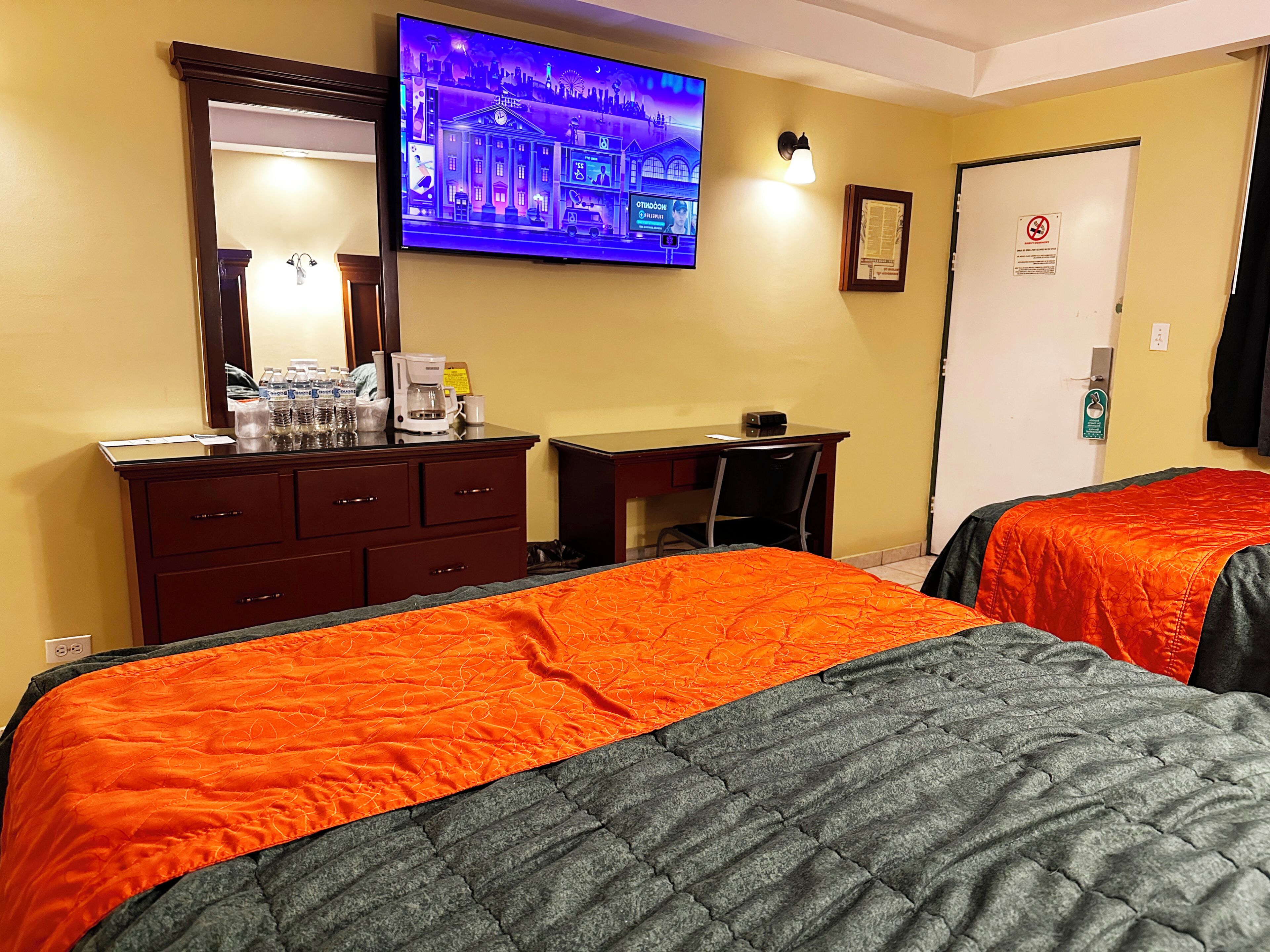 Une chambre d’hôtel avec deux lits, un bureau, une télévision et une armoire.