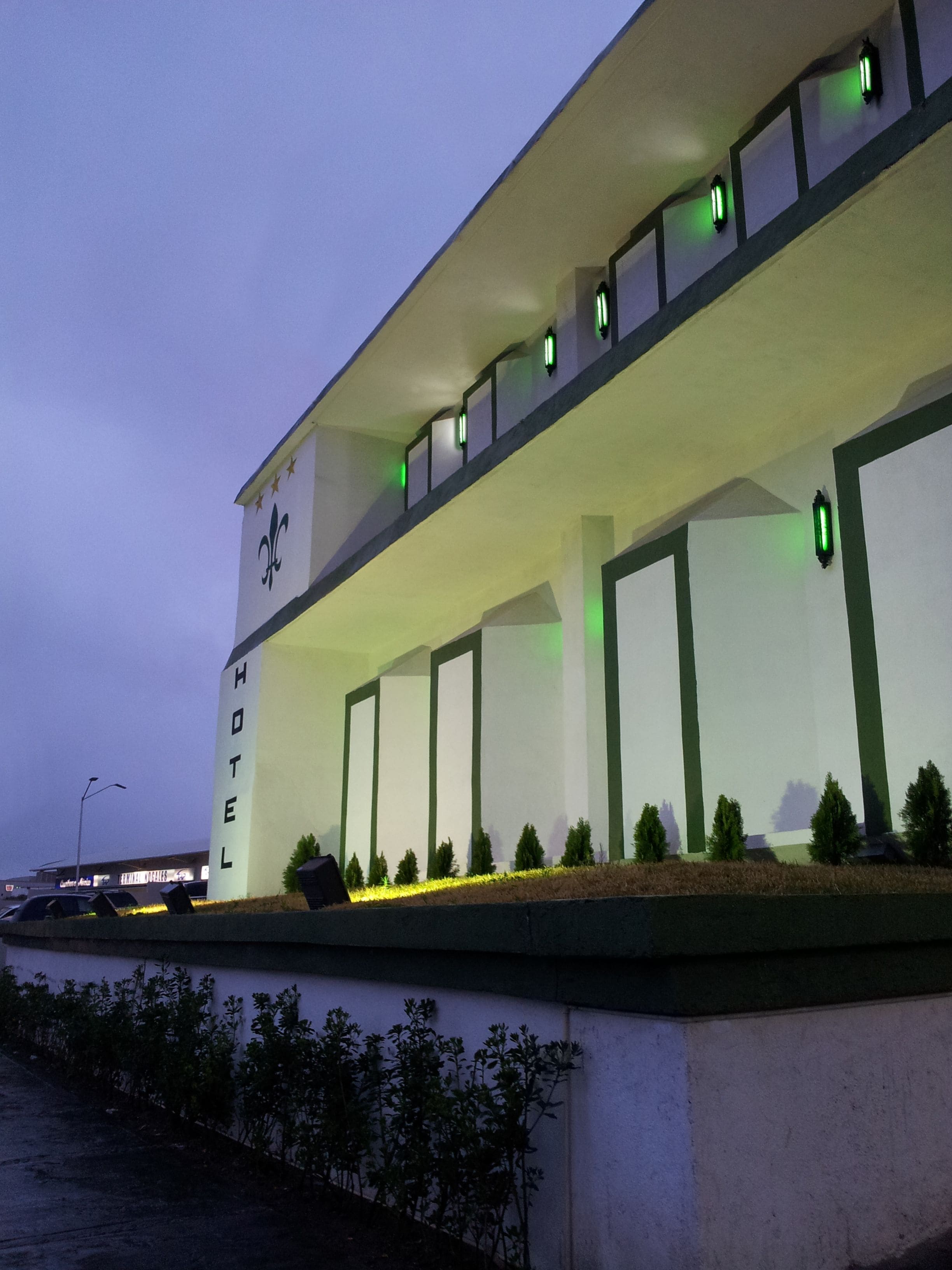 Un hôtel doté d’une façade moderne, d’un logo bien visible et d’une série de fenêtres éclairées en vert.
