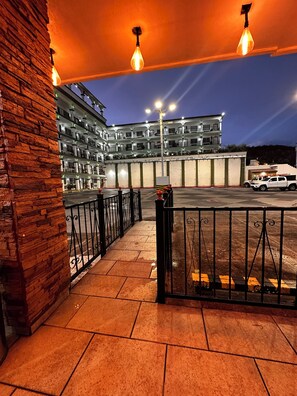 A multi-story building with a parking area in front, featuring a brick wall on the left and a metal fence. - Hotel Marques De Cima (Nogales)