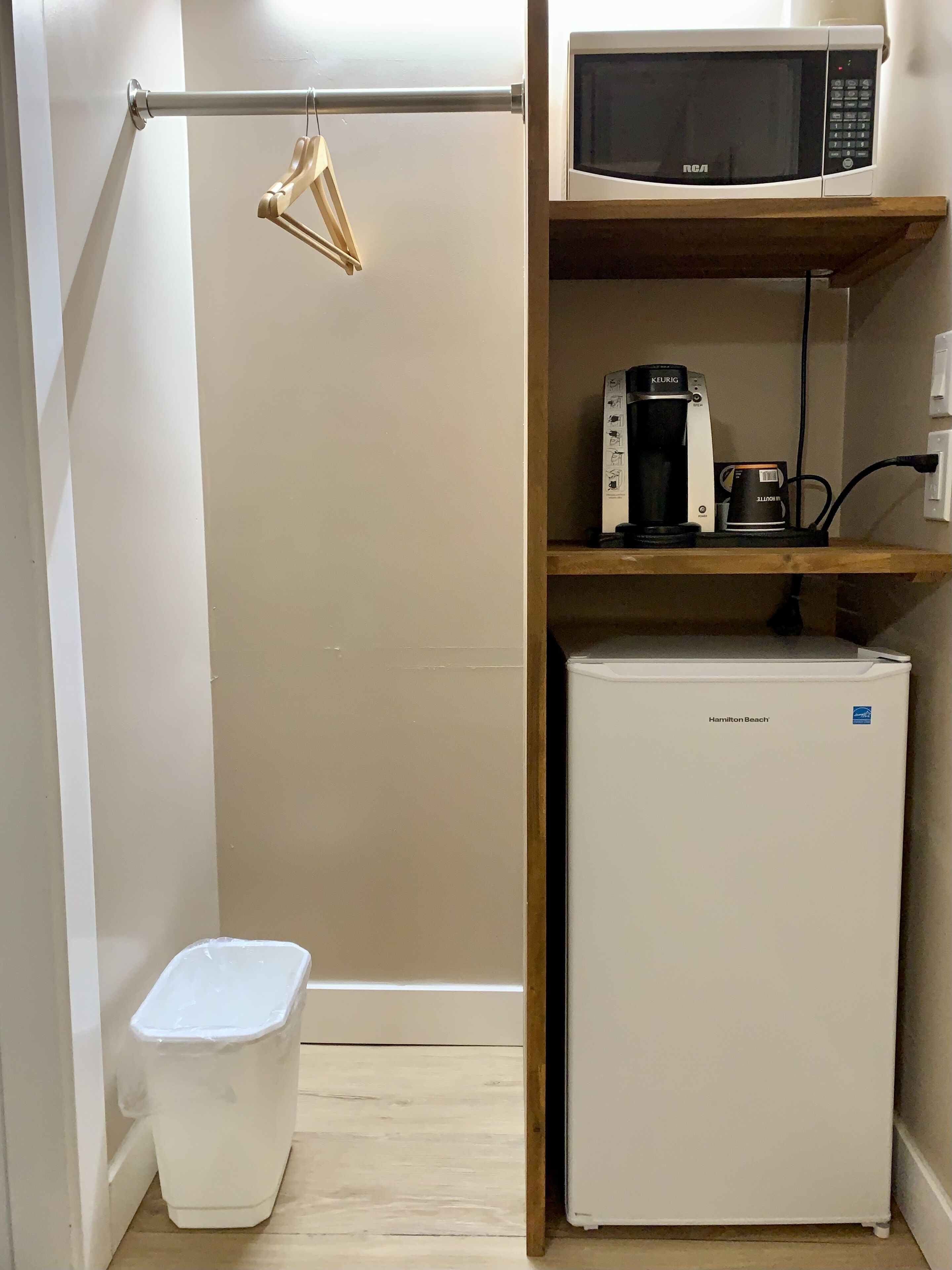 Una kitchenette compacta con microondas, cafetera y refrigerador pequeño.