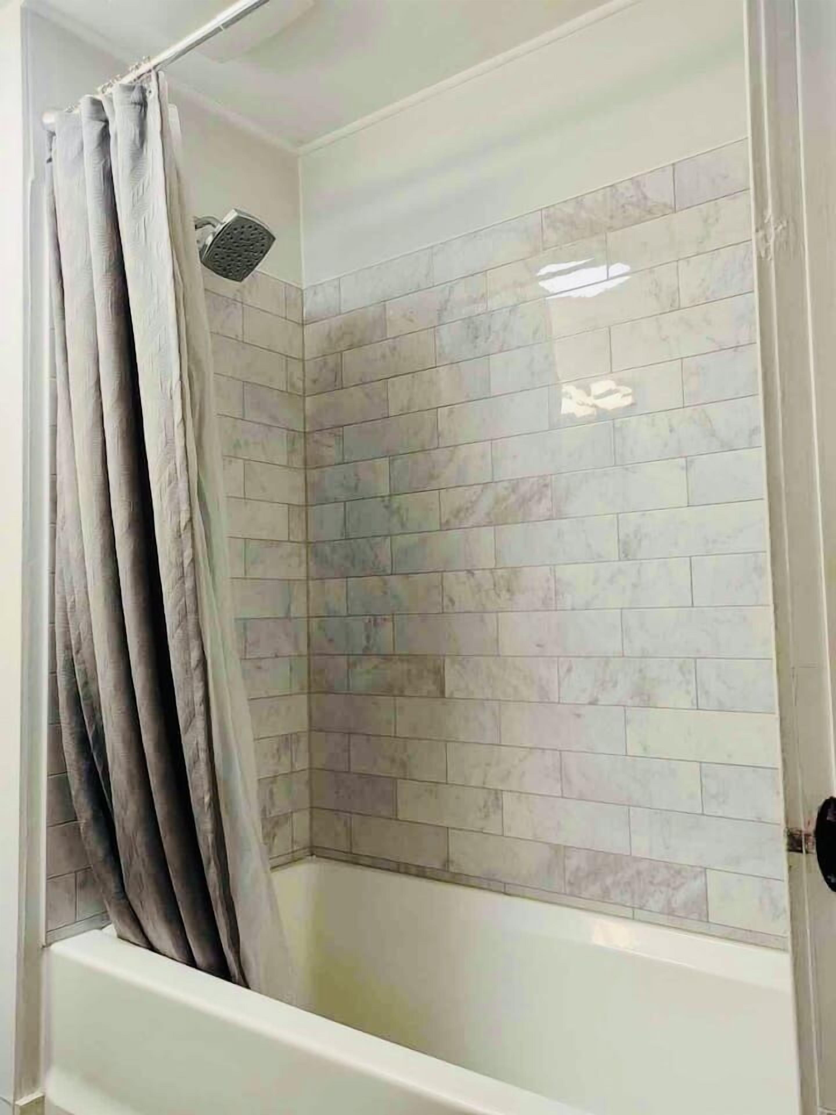 A shower area with a tiled wall and a showerhead.