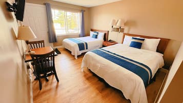 Une chambre d’hôtel avec deux lits, un bureau, une chaise, une fenêtre avec des rideaux et un luminaire au plafond.