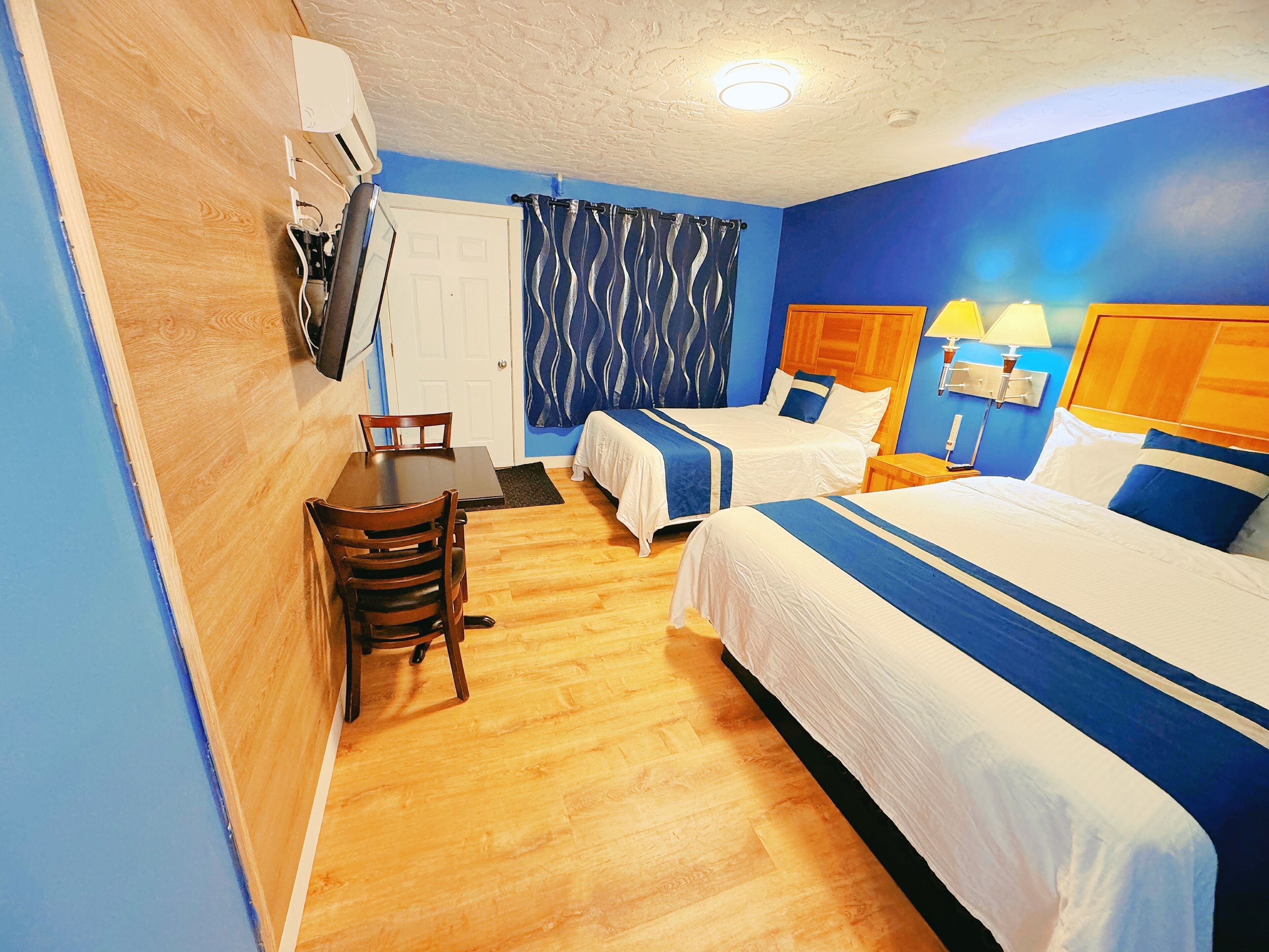 A hotel room with two beds, a dining table, and a small seating area.