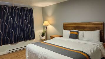 A neatly made bed with a white and gray striped bedspread, a wooden headboard, and two pillows with a gray and orange stripe.