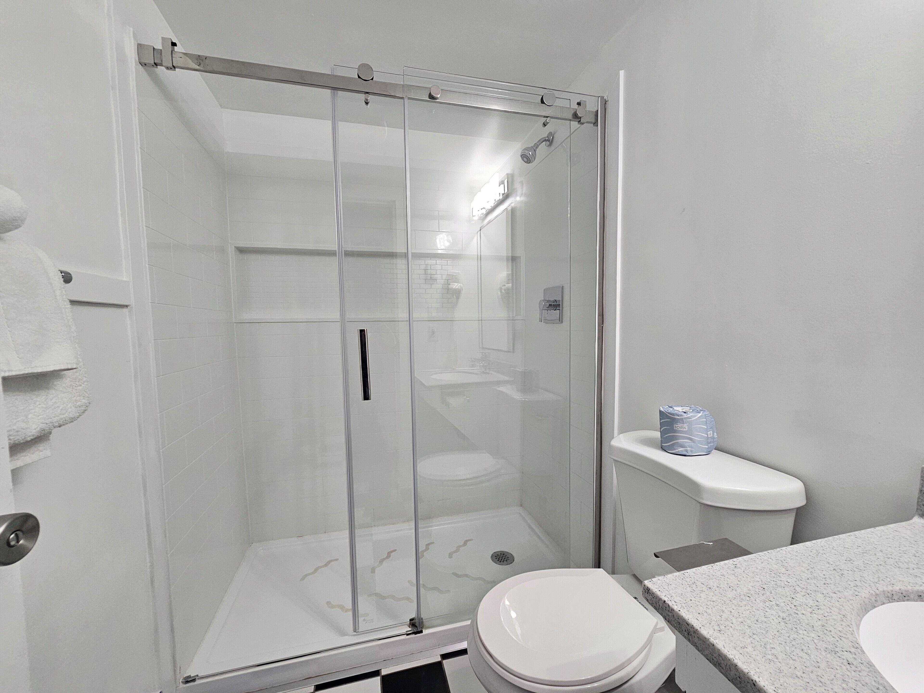 Et moderne badeværelse med en brusekabine med glasvægge, toilet og vask.
