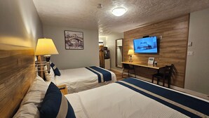 Habitación de hotel con dos camas, un escritorio, un televisor y un espejo.