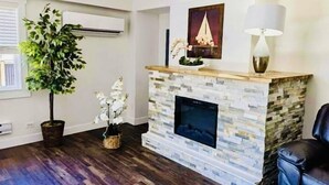 Una sala de estar con chimenea de piedra, una planta en maceta y un cuadro en la pared.
