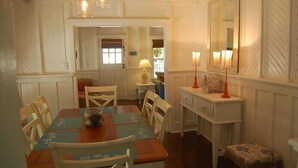 A dining area with a wooden table, chairs, and a small side table with a lamp. - The Darlington Cottages (Myrtle Beach)