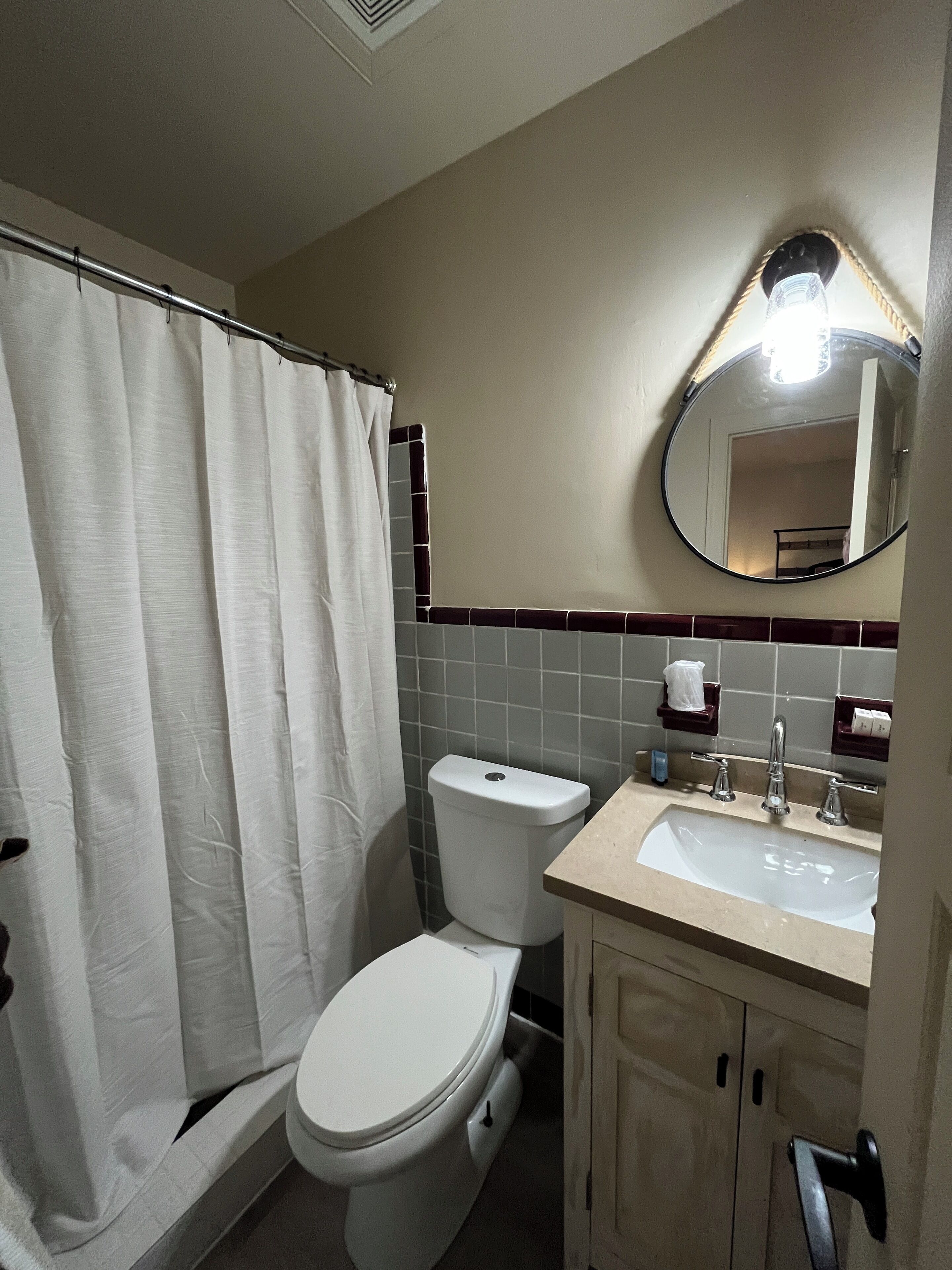 A bathroom with a toilet, sink, and mirror.