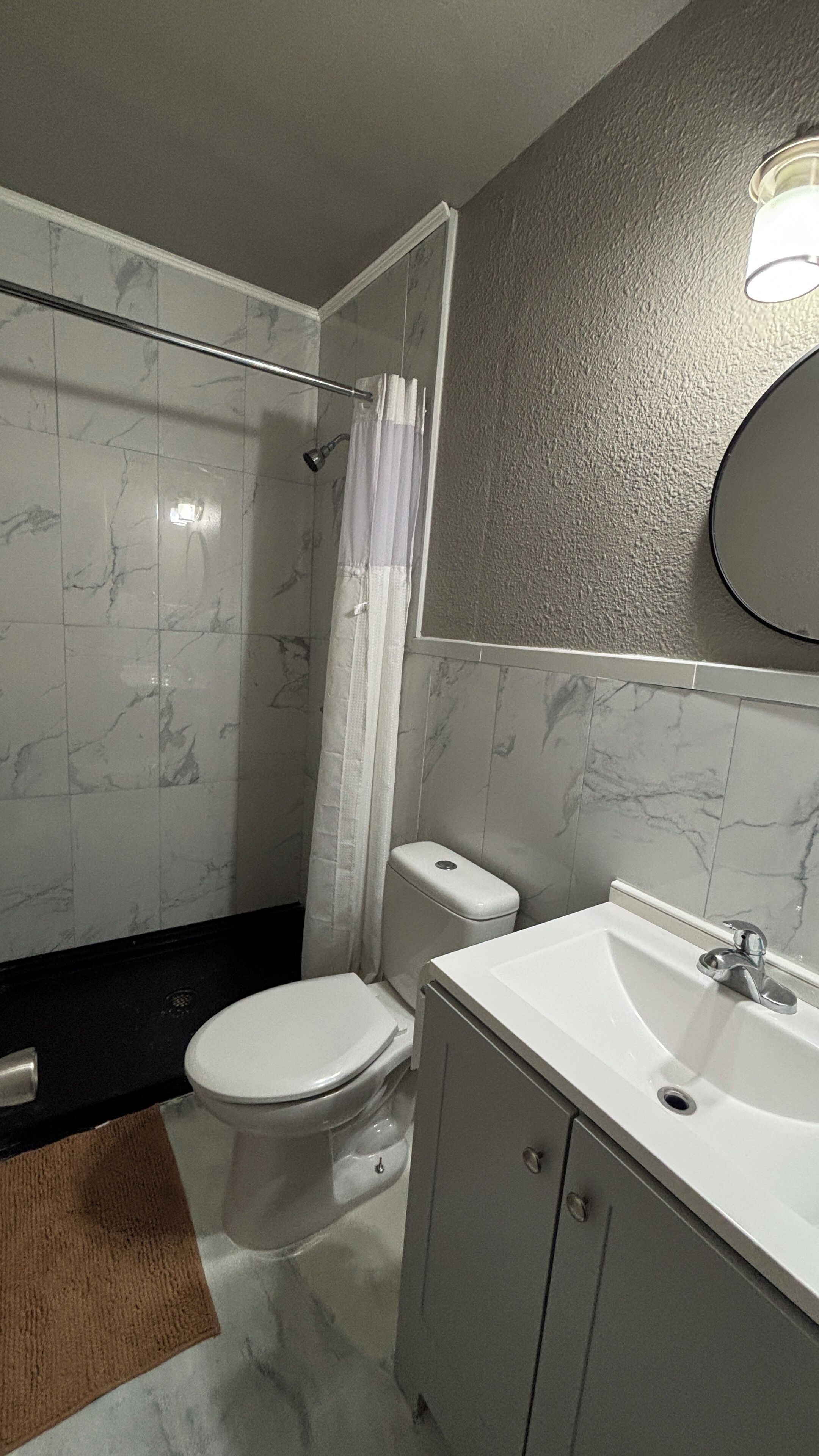 A bathroom with a toilet, sink, and shower.