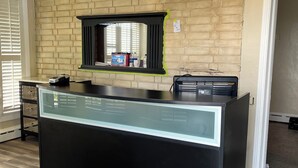 A reception desk with a glass top, a black counter, a brick wall, and a ceiling fan. - Shamrock Cove Inn (Ocala)