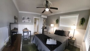 A compact bedroom with a bed, bedside tables, a desk, and a ceiling fan. - Shamrock Cove Inn (Ocala)