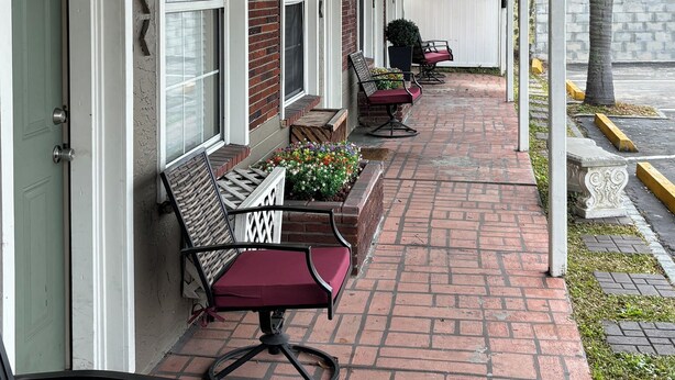 A covered porch with brick flooring, outdoor seating, and ceiling fans. - Shamrock Cove Inn (Ocala)