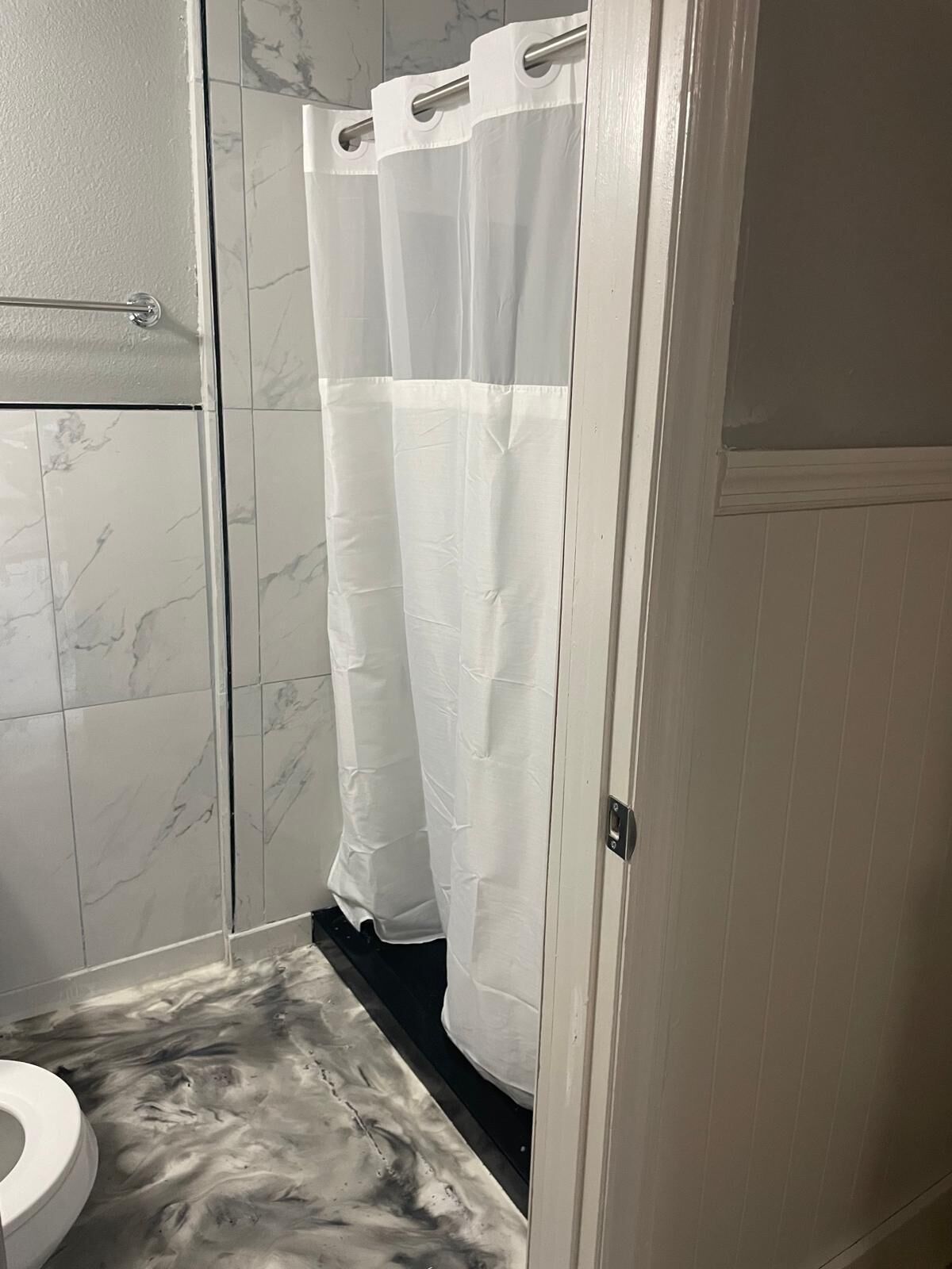Une salle de bain avec douche, toilettes et carrelage en marbre.