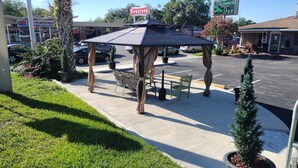A gazebo with a roof, a bench, and a small table. - Shamrock Cove Inn (Ocala)