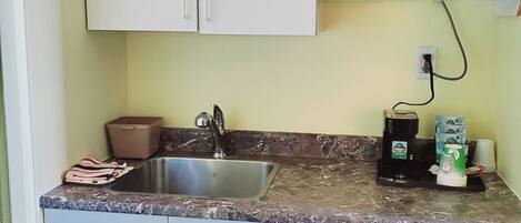 A compact kitchen with a sink, a microwave, and a coffee maker.