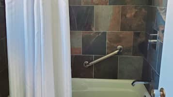 Un baño con bañera, cortina de ducha y paredes de azulejos.