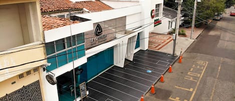 Entrada de hotel de diseño moderno, con una escalera visible y conos de tráfico naranja que indican obras o mantenimiento.
