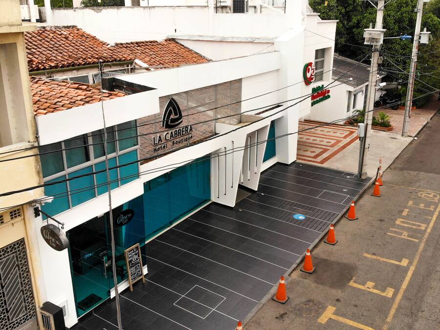 Entrada de hotel de diseño moderno, con una escalera visible y conos de tráfico naranja que indican obras o mantenimiento.