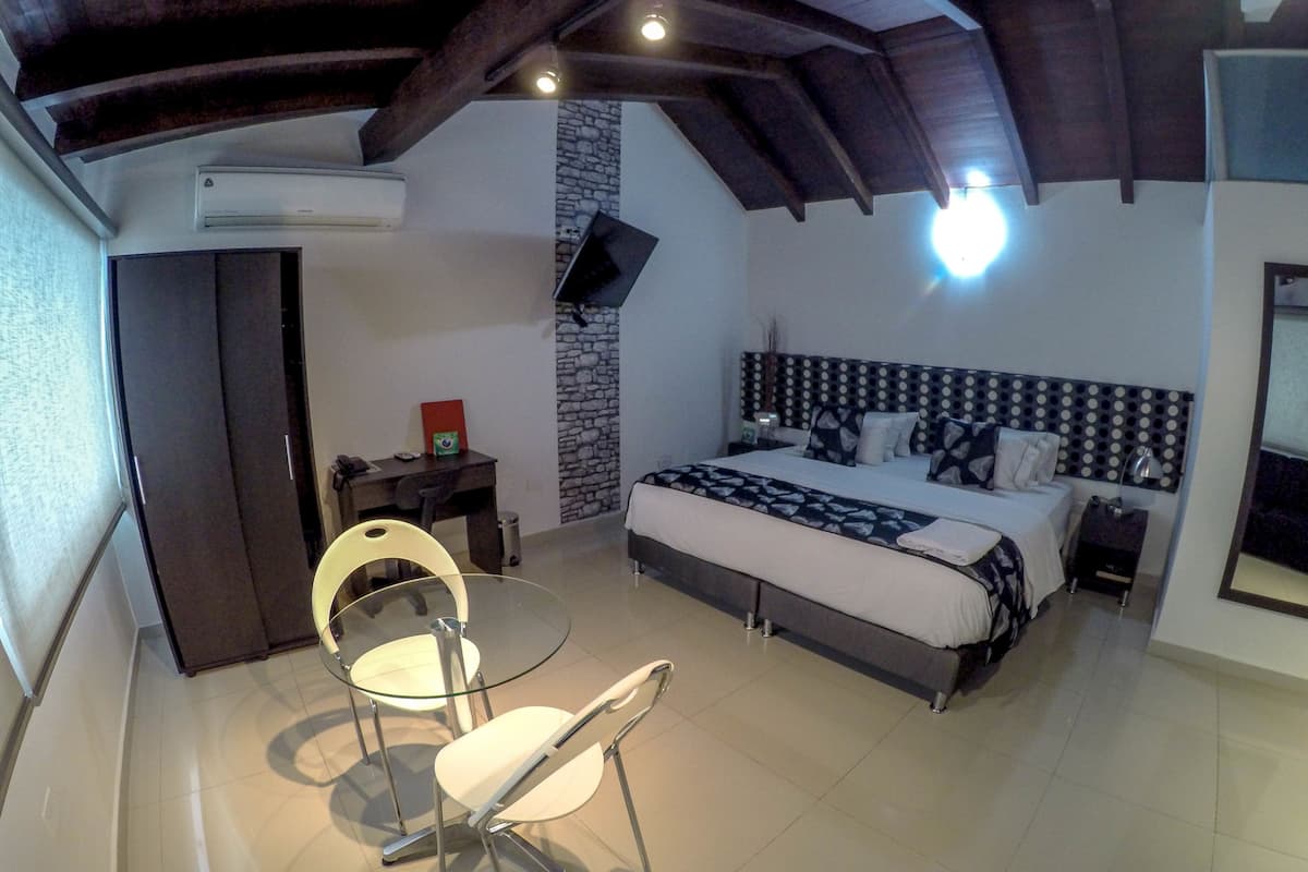 Ein Schlafzimmer mit einem Bett, einem Fernseher, einem Schreibtisch und einem Stuhl.