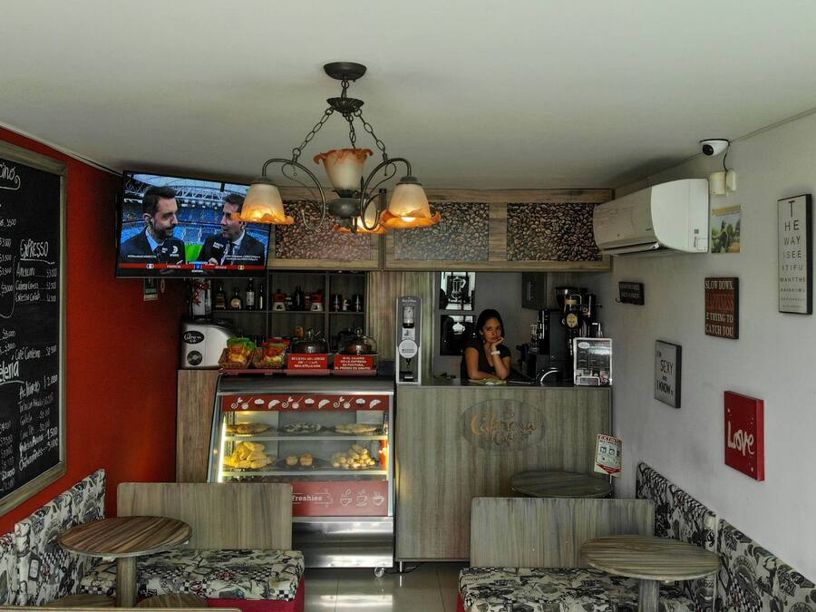 A cafe with a TV displaying sports, a coffee machine, and a chalkboard menu.