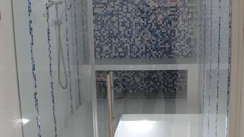 Eine gläserne Dusche mit mosaikbesetzter gefliester Wand und weißem Boden.