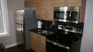 Una cocina moderna con electrodomésticos de acero inoxidable, armarios de madera y encimera negra.