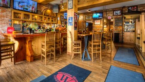 A bar area with wooden furniture, a bar counter, and multiple televisions mounted on the walls. - Western Hotel & Executive Suites (Guelph)
