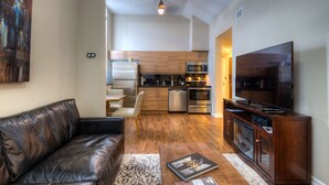 A modern kitchen with stainless steel appliances, a dining area with a leather couch, and a flat-screen TV. - Western Hotel & Executive Suites (Guelph)