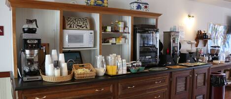 A kitchen area with a coffee machine, microwave, and various food items on the counter.