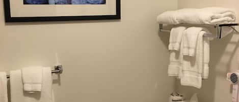 A bathroom with a toilet, a sink, a towel rack, and a framed picture of blueberries on the wall.