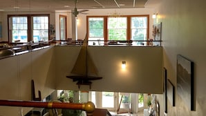 Ruime kamer met hoge plafonds, grote ramen en een balkon met een model zeilboot.