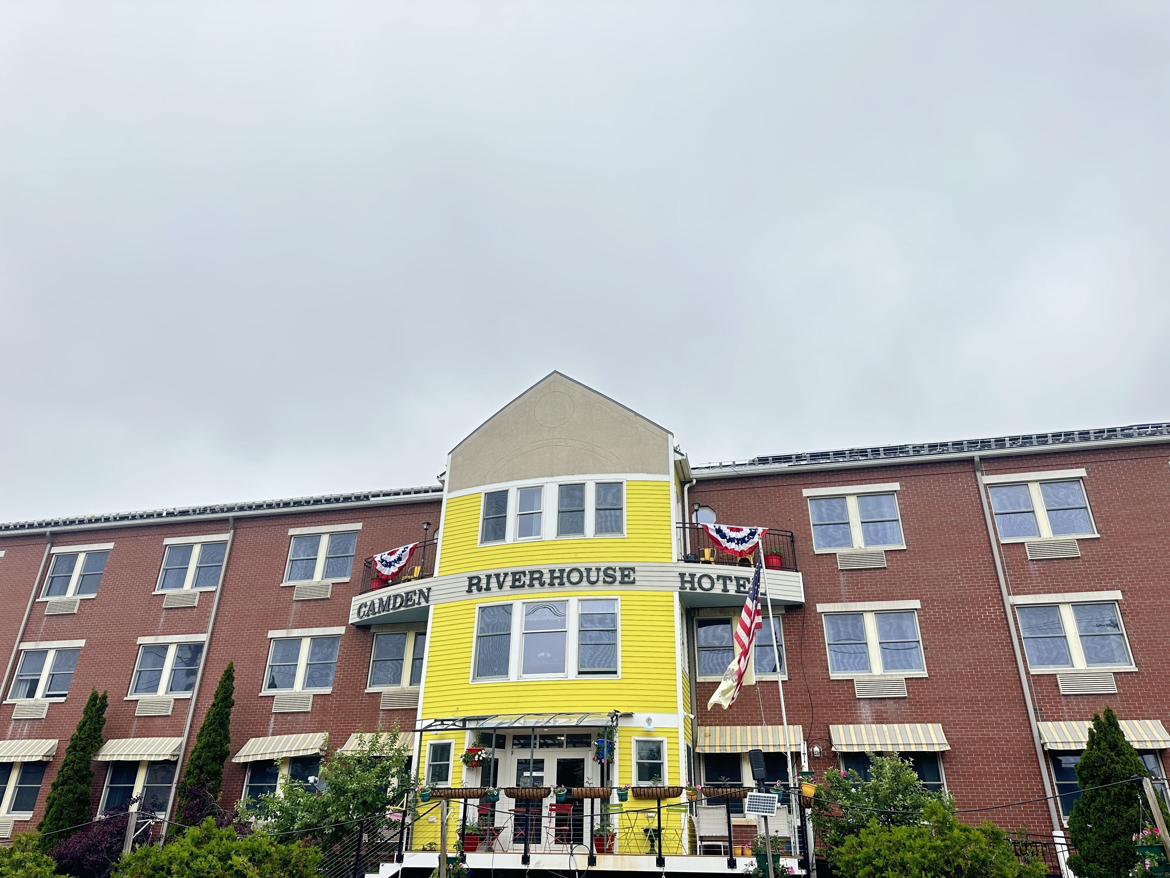 Un immeuble à plusieurs étages, sur lequel on peut voir une enseigne jaune indiquant le Riverhouse Hotel.