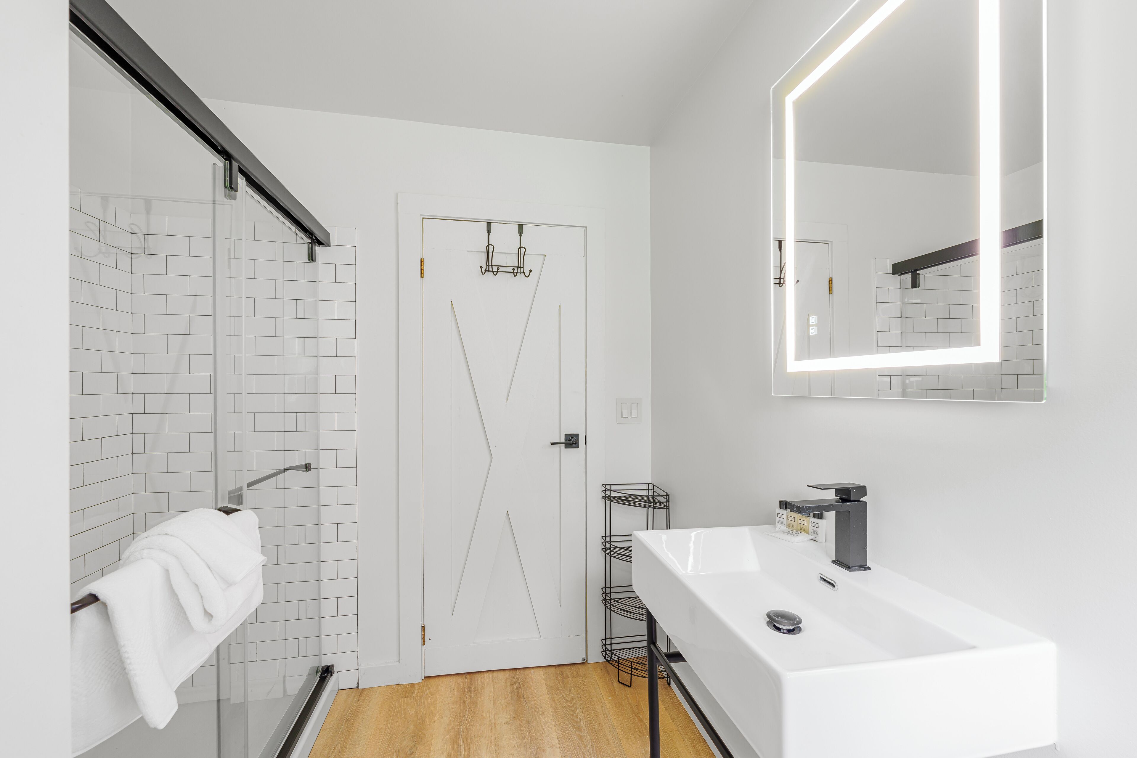 A modern bathroom with a white sink, mirror, and towel rack.