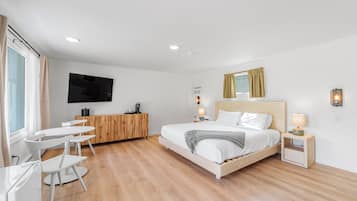 Quarto de hotel moderno com cama, mesas de cabeceira, escrivaninha e televisão.