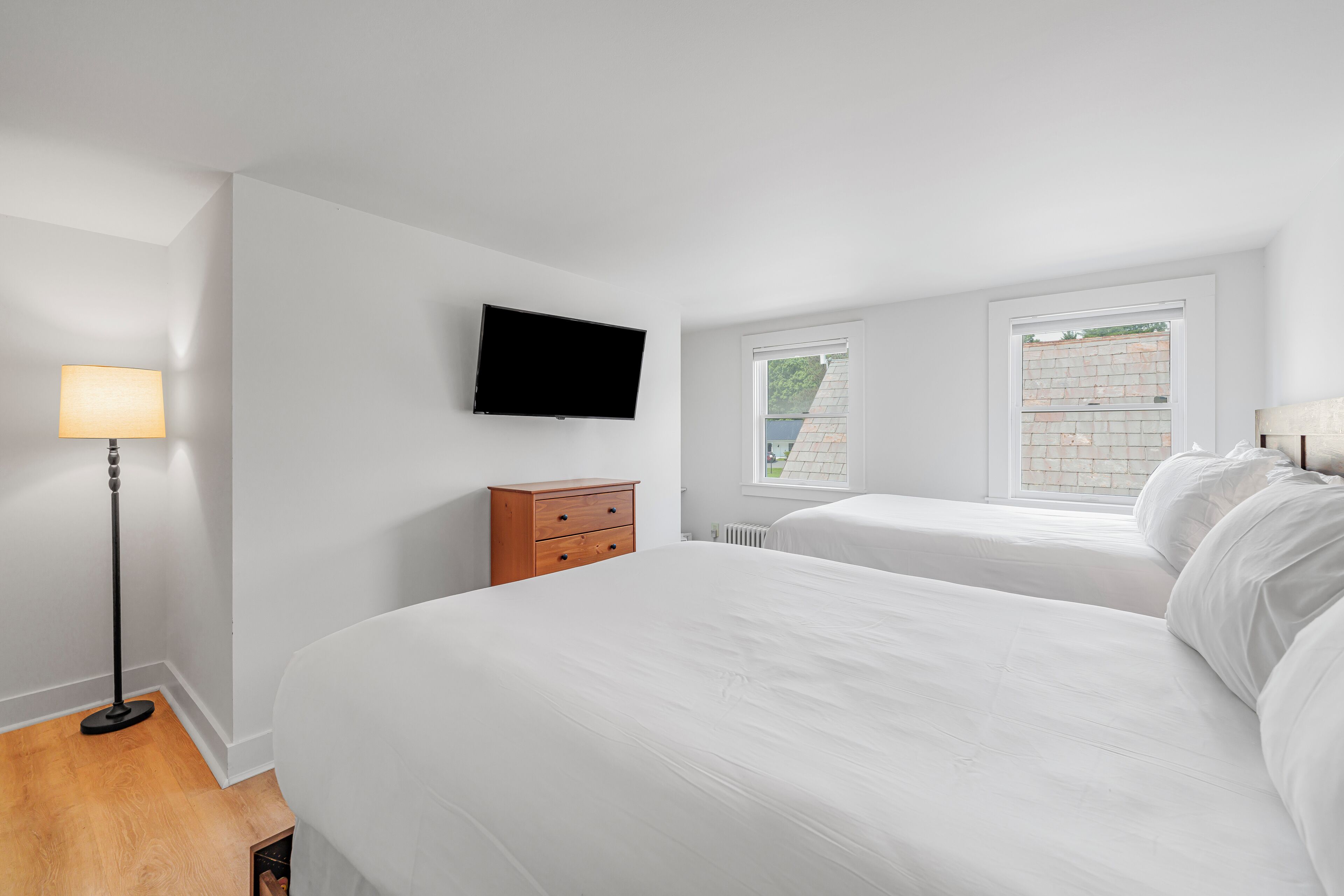 A bedroom with two beds, a TV, a lamp, and a dresser.