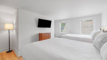 A bedroom with two beds, a TV, a lamp, and a dresser.