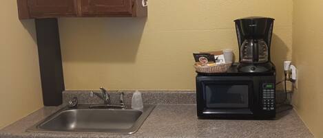A kitchen with a sink, a microwave, a coffee maker, and a dishwasher.