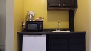 A compact kitchenette with a microwave, coffee maker, and a small refrigerator.