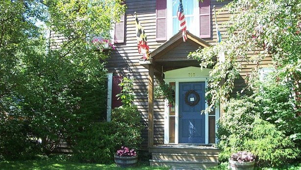 A house with a blue front door, a wreath above it, and two American flags on the roof. - Chesapeake Inn of Lenox (Lenox)